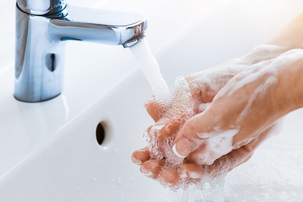 Mani insaponate sotto l'acqua del rubinetto