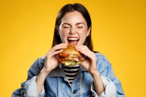 Ragazza felice che mangia un hamburger