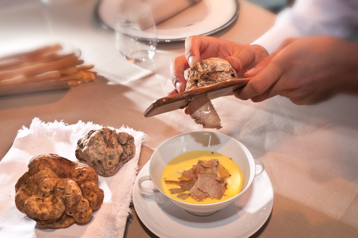 Chef che grattugia tartufo bianco  dentro ad una ciotola 