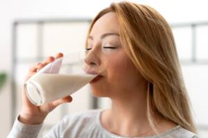 Ragazza bionda che beve un bicchiere di latte