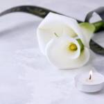 Composizione funebre con calla, nastro nero e lumino