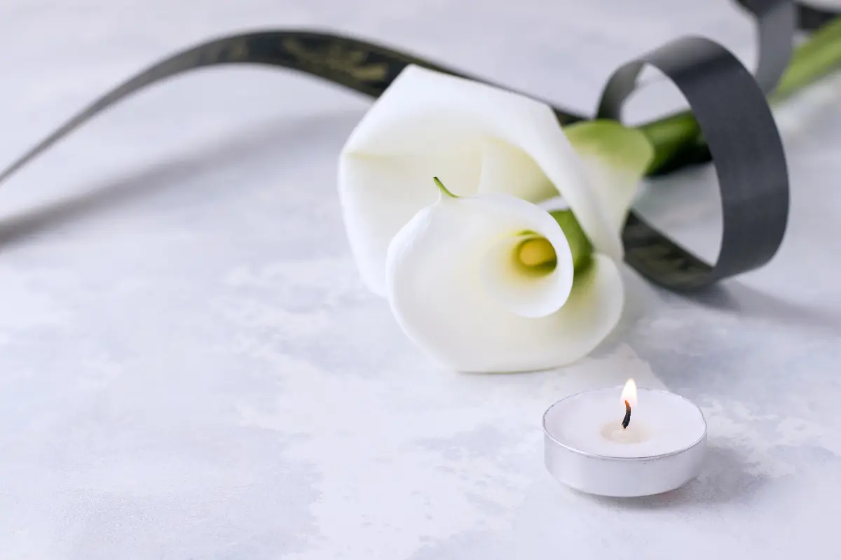 Composizione funebre con calla, nastro nero e lumino