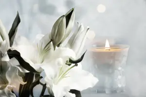 Composizione floreale con gigli e luce soffusa di un cero