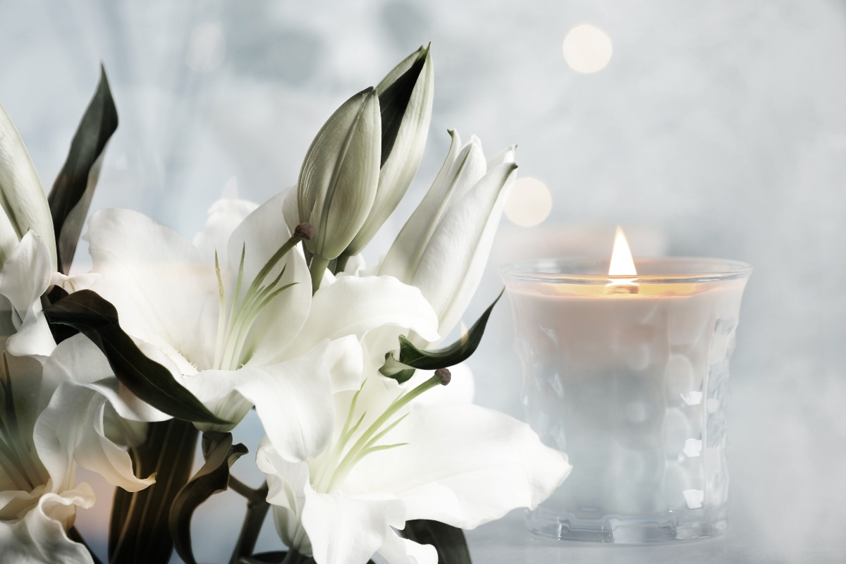Composizione floreale con gigli e luce soffusa di un cero