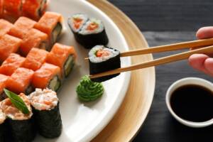 Grazie a delle bacchette, una persona prende un pezzo di sushi da un piatto