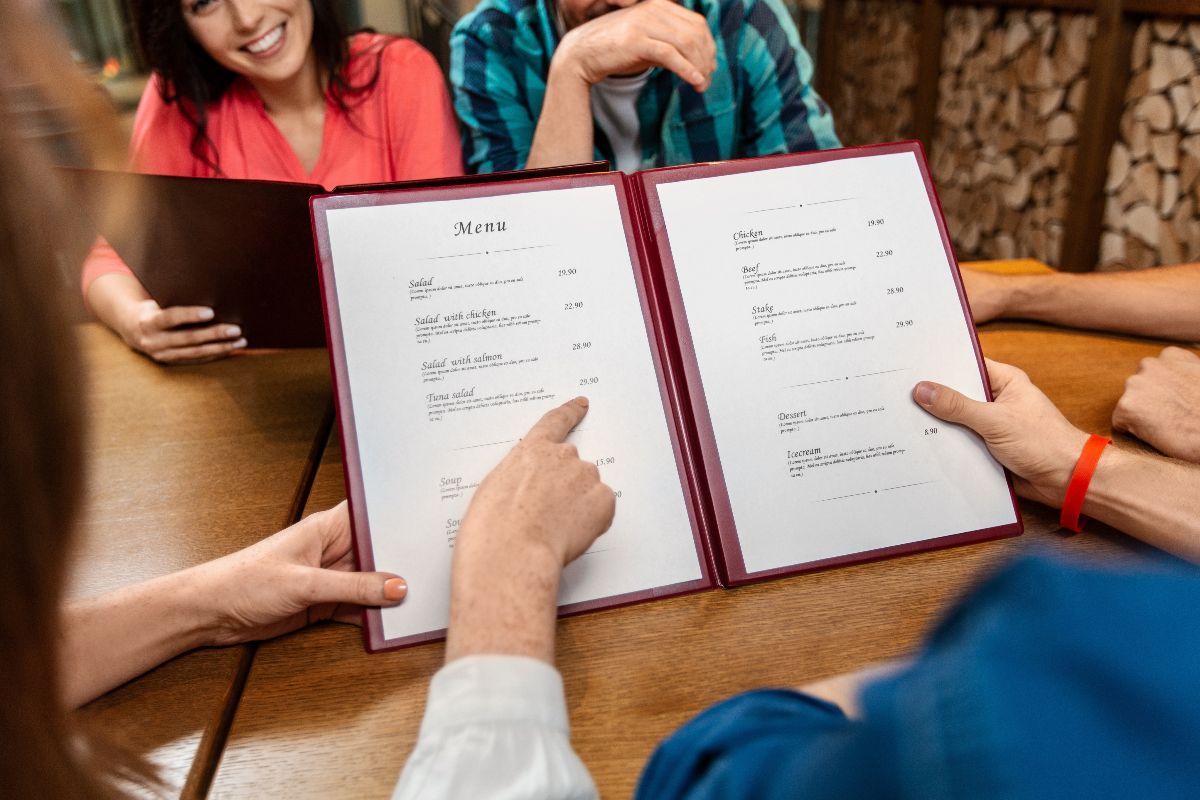 Amici che scelgono i piatti dal menù del ristorante.
